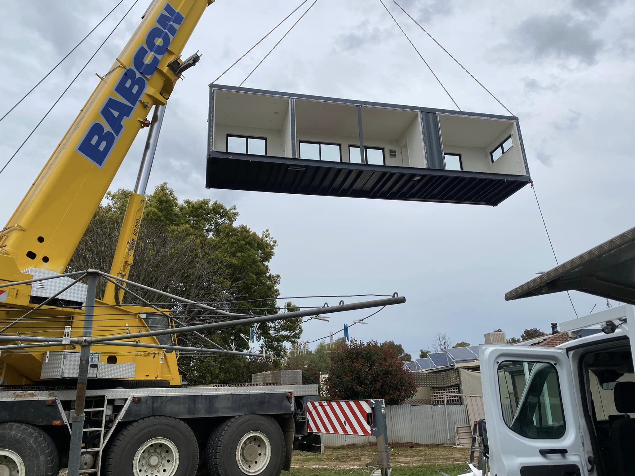Modular building being lifted by a crane with 'Barcon' branding.